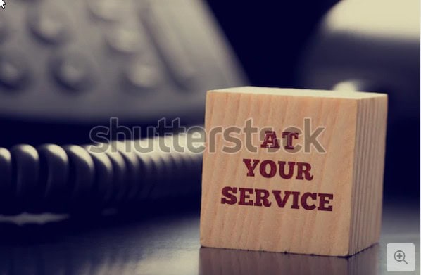 Kundendienst-Schild mit der Aufschrift 'At Your Service' auf Holzblock.